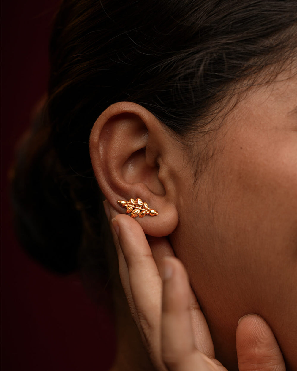 Woman wearing a leaf-shaped gold-plated Parna silver earring 